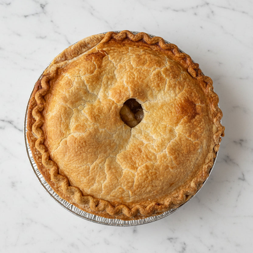 Small apple pie in a metal pie dish on a dark surface